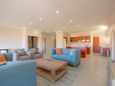 a living room with two blue chairs and a coffee table at Highland Gate Ferox Creek in Dullstroom