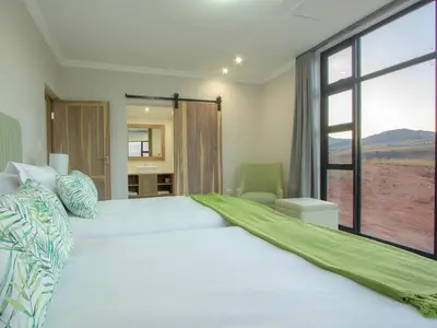 a bedroom with a large bed with a large window at Highland Gate Ferox Creek in Dullstroom