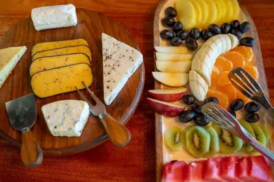 a plate of cheese and fruit on a wooden table at Sunbirds Oasis Lodge in Hoedspruit