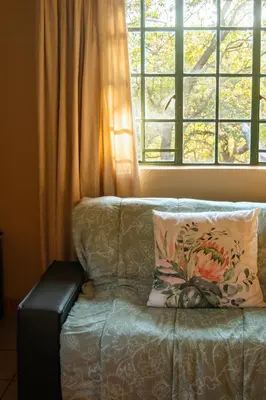 a couch sitting in front of a window at Mackers Self Catering Cottages in Hazyview