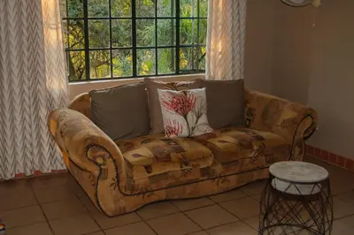 a couch in a living room with a window at Mackers Self Catering Cottages in Hazyview