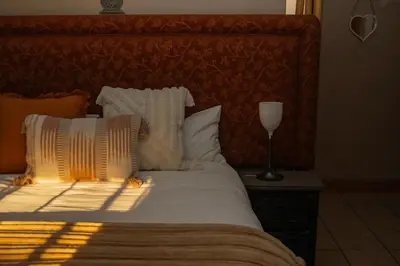 a bed with white pillows and a lamp on a table at Mackers Self Catering Cottages in Hazyview