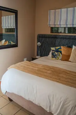 a bedroom with a large bed and a mirror at Mackers Self Catering Cottages in Hazyview