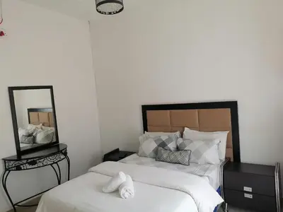 a bedroom with two beds with white sheets and a mirror at FRANCHISE BENONI GUEST HOUSE in Benoni