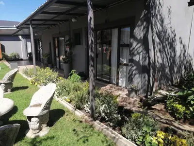 a yard with benches in front of a house at FRANCHISE BENONI GUEST HOUSE in Benoni
