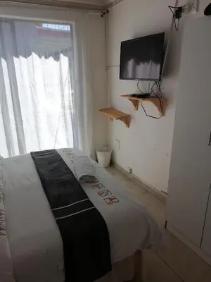 a bedroom with a bed and a flat screen tv at FRANCHISE BENONI GUEST HOUSE in Benoni