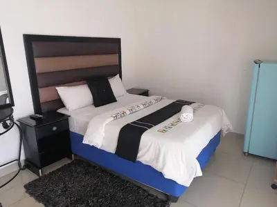 a bedroom with a bed with a black and white comforter at FRANCHISE BENONI GUEST HOUSE in Benoni