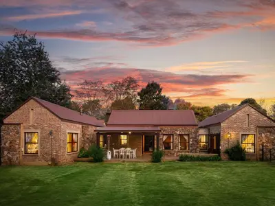 a stone house with a sunset in the background at 295 on Ingwenya in Dullstroom