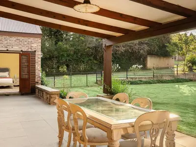 a patio with a table and chairs under a wooden pergola at 295 on Ingwenya in Dullstroom