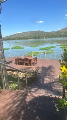 a table and chairs in front of a body of water at The Sanctum in Hartbeespoort