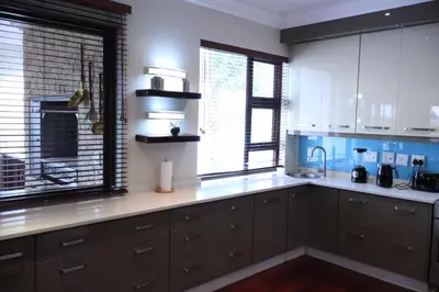 a kitchen with white cabinets and a large window at The Sanctum in Hartbeespoort