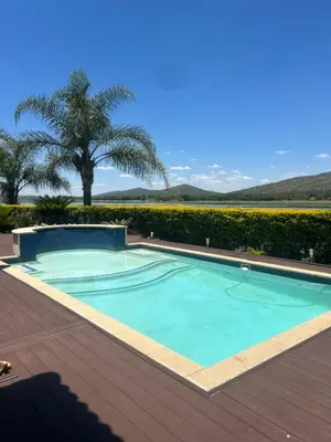 a swimming pool on a deck with a palm tree at The Sanctum in Hartbeespoort