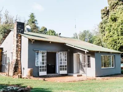 a small white house with a brick chimney at Cussonia Cottage in Haenertsburg
