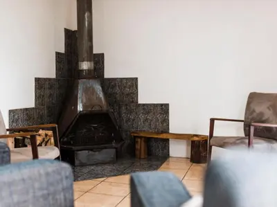 a living room with a fireplace and two chairs at Cussonia Cottage in Haenertsburg