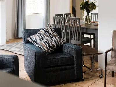 a living room with a chair and a dining room table at Cussonia Cottage in Haenertsburg