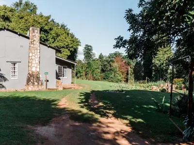 a house with a brick chimney next to a yard at Cussonia Cottage in Haenertsburg