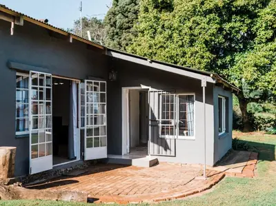 a house with white doors and a porch at Cussonia Cottage in Haenertsburg