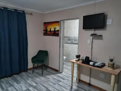 a room with a television and a desk with a chair at Ribeng la Noka Conference and Leisure Center in Ga-Ramokadi-kadi