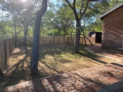 a brick yard with trees and a fence at Vlakkieskraal Farmstay - BushBaby House in Bela-Bela
