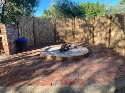 a brick patio with a fountain in front of a fence at Vlakkieskraal Farmstay - BushBaby House in Bela-Bela