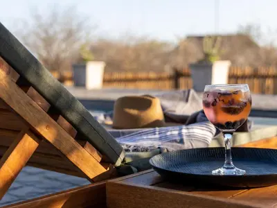 a glass of wine sitting on a table with a plate at Muunga Bush Lodge & Spa in Hoedspruit