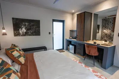 a bedroom with a bed and a desk and a sink at Muunga Bush Lodge & Spa in Hoedspruit