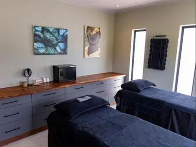 a bedroom with two beds and a desk with a microwave at Muunga Bush Lodge & Spa in Hoedspruit