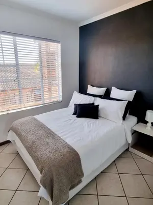 a bedroom with a large white bed and a window at Home away from home in Centurion