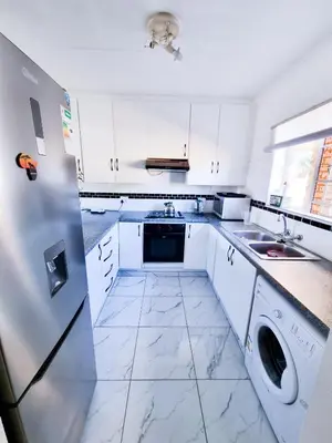 a white kitchen with a sink and a refrigerator at Home away from home in Centurion
