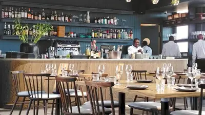a restaurant with wooden tables and chairs and a bar at Menlyn Maine Residences - Superior king - Paris apartment in Pretoria