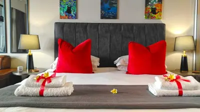 a bedroom with red pillows and towels on a bed at Menlyn Maine Residences - Superior king - Paris apartment in Pretoria