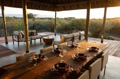 a wooden table with wine glasses on a patio at Villa Tall Horse - Zandspruit Bush and Aero Estate in Hoedspruit