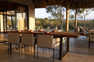 a dining room with a wooden table and chairs at Villa Tall Horse - Zandspruit Bush and Aero Estate in Hoedspruit