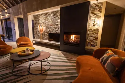 a living room with a fireplace and orange furniture at Villa Tall Horse - Zandspruit Bush and Aero Estate in Hoedspruit