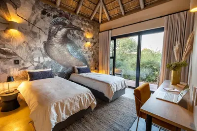 a bedroom with two beds and a mural of a bird at Villa Tall Horse - Zandspruit Bush and Aero Estate in Hoedspruit