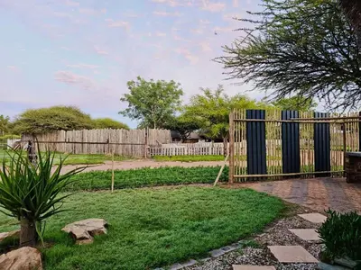 a fence in a backyard with a yard with grass at Unique Overnight Polokwane in Polokwane