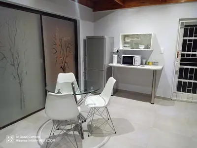 a kitchen with a glass table and white chairs at 4 on Verbena in Boksburg