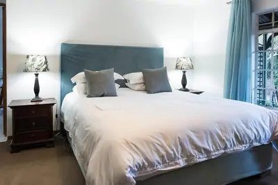a bedroom with a large white bed with two lamps at Willow Cottage in Dullstroom