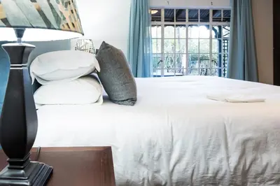 a bedroom with a bed with pillows and a lamp at Willow Cottage in Dullstroom