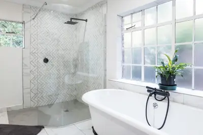 a white bathroom with a tub and a shower at Willow Cottage in Dullstroom
