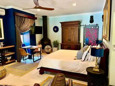 a bedroom with blue walls and a bed and a desk at Forty 4 On Hoog in Polokwane