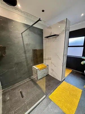 a bathroom with a glass shower with a yellow rug at Forty 4 On Hoog in Polokwane