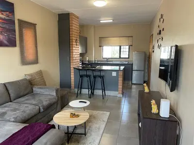 a living room with a couch and a kitchen at Mall of Africa Spot By Damo in Midrand