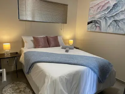 a bedroom with a large white bed with two lamps at Mall of Africa Spot By Damo in Midrand