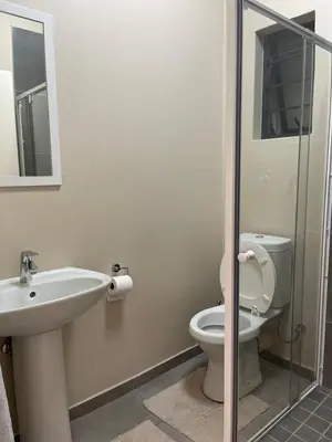 a bathroom with a sink and a toilet and a mirror at Mall of Africa Spot By Damo in Midrand