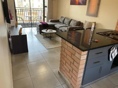 a kitchen and living room with a couch and a table at Mall of Africa Spot By Damo in Midrand