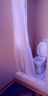 a bathroom with a toilet with a shower curtain at Thully Teams in Nelspruit