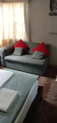 two beds in a room with a couch and red pillows at Thully Teams in Nelspruit