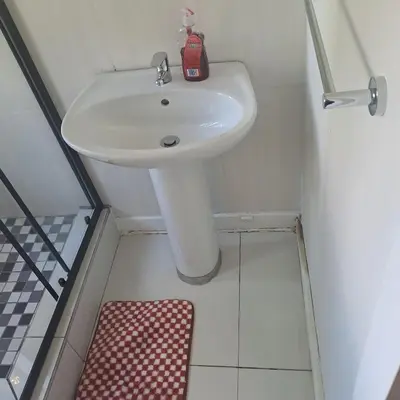 a bathroom with a white sink and a red soap dispenser at Moonlight Guesthouse in Pretoria