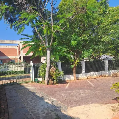 a park with trees in front of a fence at Moonlight Guesthouse in Pretoria